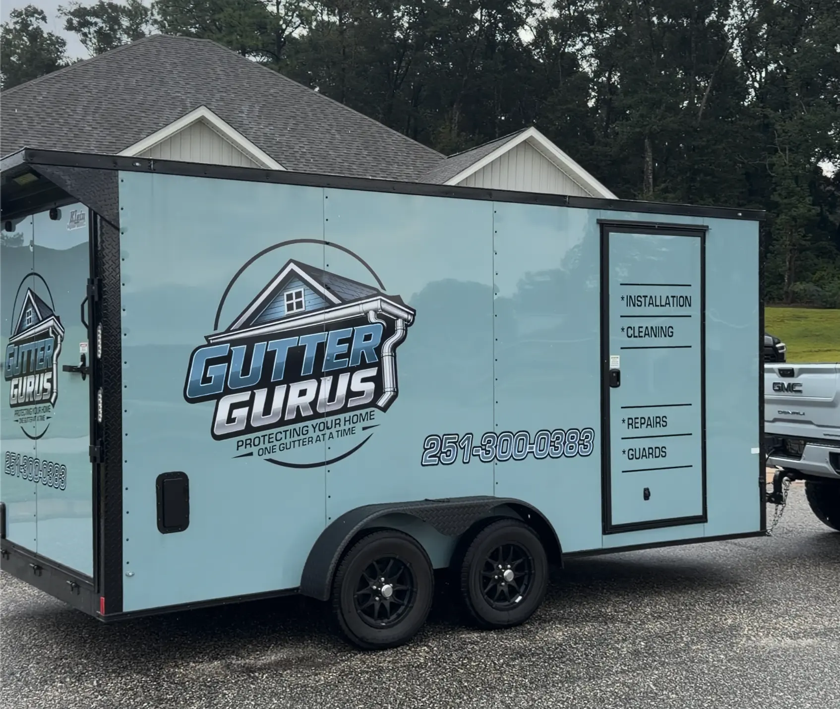 Gutter Gurus trailer wrapped with the company logo, phone number, and services list